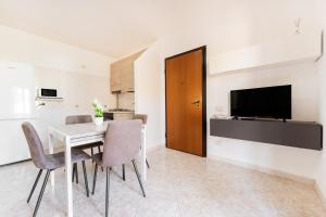 a dining room with a table and chairs and a television at Colombo Rooms in Sestu