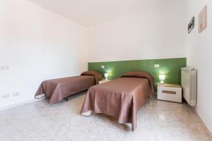 two beds in a room with green walls at Colombo Rooms in Sestu