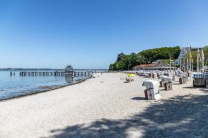 a beach with chairs and a pier in the water at Ferienwohnung mit Badestrand in Glücksburg