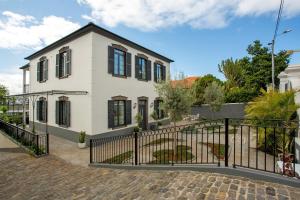 a white house with black windows and a fence at Vila Francisco in Funchal