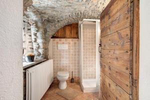 a bathroom with a toilet and a wooden door at La Maison de Karen The Deer House in Gignod +21 photos