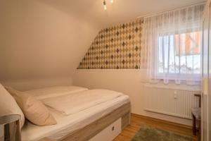 a small bedroom with a bed and a window at Ferienwohnung Schürer in Meckenbeuren