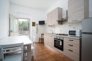 a kitchen with white cabinets and a table with a microwave at Casa Picchereddu in Orosei