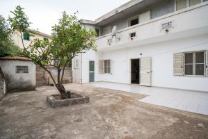 a white building with a tree in the courtyard at Casa Picchereddu in Orosei
