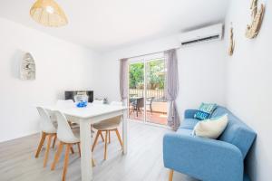a living room with a blue couch and a table and chairs at Gran Sol Family 2 in Felanitx
