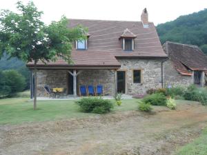 a stone house with blue chairs in the yard at La Maison Leontine in Cahus