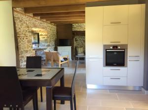 a kitchen with white cabinets and a table with a television at La Maison Leontine in Cahus