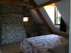 a bedroom with a bed and a stone wall at La Maison Leontine in Cahus