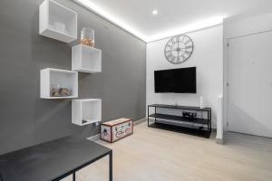 a living room with a table and a tv and a clock at Kaixo in Calafell