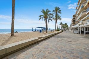 a cobblestone street next to a beach with palm trees at Kaixo in Calafell