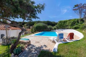 a swimming pool with two lawn chairs and a swimming poolvisor at Villa Sabbia - Private pool in Stintino