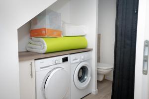 a bathroom with a washing machine and a toilet at Gite La Maison Du Soyeux Ga in Les Abrets en Dauphine