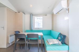 a room with a blue couch and a table and chairs at Mobilhomelaco34 in Vendres
