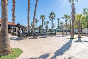 a park with palm trees and chairs and a playground at Mobilhomelaco34 in Vendres