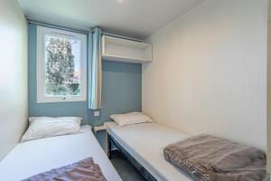 two beds in a small room with a window at Mobilhomelaco34 in Vendres +17 photos