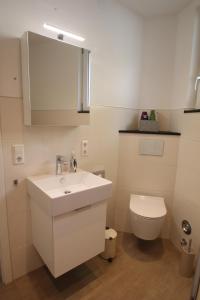 a bathroom with a white sink and a toilet at Ferienwohnung am Stadtwall in Stockach +14 photos