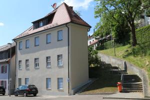 a white building with a staircase next to a hill at Ferienwohnung am Stadtwall in Stockach