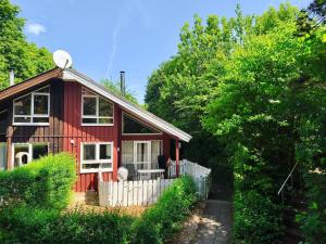 a red house with a white fence and trees at Extertal Ferienpark Haus Sonnental in Extertal