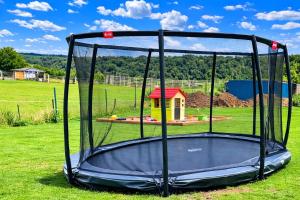 a trampoline in a field with a playground in the background at Extertal Ferienpark Haus Sonnental in Extertal