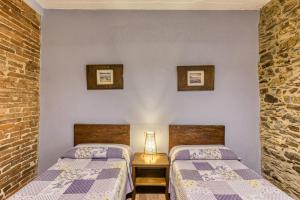 a bedroom with two beds and a lamp on a table at Casa Rural El Torn in Garriguella
