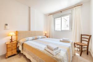 a bedroom with a bed and a chair and a window at Talaia 1a in Port de Pollensa