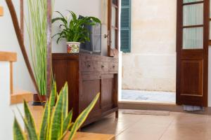 a room with a tv on a wooden cabinet with plants at Ses Andrones 3 in Ciutadella