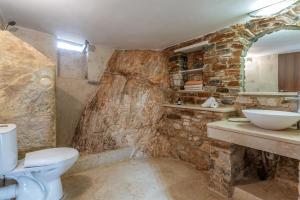 a stone bathroom with a toilet and a sink at Vrahos Tinos in Panormos +16 photos