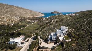 an aerial view of a house on a hill next to the ocean at Vrahos Tinos in Panormos