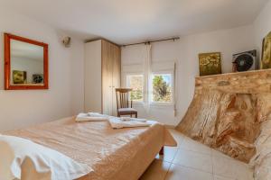 a bedroom with a bed and a chair and a window at Vrahos Tinos in Panormos
