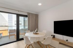 a living room with a table with chairs and a television at Lupama Suite in Arguineguín