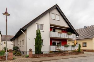 a white house with red trim and a white balcony at Ferienwohnung Walter in Ringsheim