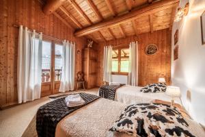 two beds in a room with wooden walls at Chalet 3 Etoiles - Le pèlouêt in Morzine