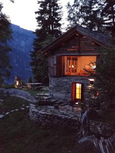 a small stone cabin with a window and a truck in the background at Chalet Atmosfera Res Albert in San Guglielmo