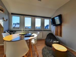 a living room with a table and chairs and a tv at Ferienwohnung Möwennest by Deju in Norderney