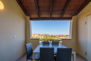 a dining room with a table and chairs and a large window at Casa Vacanze Cocco in Porto San Paolo