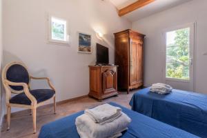 a bedroom with two beds and a chair and a tv at Maison d'hôtes Collobrières in Collobrières