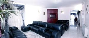 a living room with black leather couches and a tv at Hotel Alceste in Marinella di Selinunte