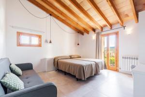 a bedroom with a bed and a couch and a window at Cases d’Alcudiarrom in Vilafranca de Bonany +19 photos