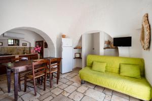 a living room with a green couch and a table at Villa Trullo Ulivo with pool in Carovigno