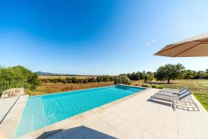 an image of a swimming pool with an umbrella at Cases d’Alcudiarrom in Vilafranca de Bonany