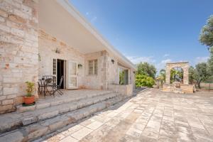 a stone house with a patio with stairs at Villa Trullo Ulivo with pool in Carovigno