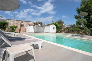 a swimming pool with a table and chairs next to a house at Villa Trullo Ulivo with pool in Carovigno