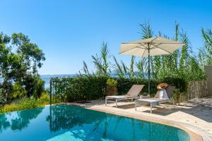a swimming pool with an umbrella and two chairs and an umbrella at Villa Armonia in Pyrgi