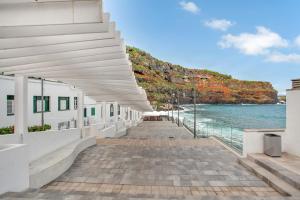 a white building with a walkway next to the ocean at Arcoiris Al Mar Playa San Marcos in San Marcos