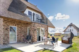two people sitting at a table outside of a house at Reethaus Nordlicht A Top-class in Dranske