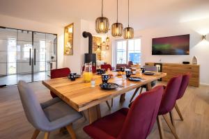 a dining room with a wooden table and red chairs at Reethaus Nordlicht A Top-class in Dranske