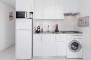 a white kitchen with a refrigerator and a washing machine at Cala en Forcat in Menorca