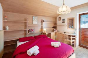 a bedroom with a red bed with two white towels at Ciasa Giorgina a Pozza di Fassa in Pozza di Fassa
