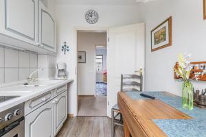 a kitchen with white cabinets and a wooden table at Alte Bäckerei - Nis Puk in Rodenäs +10 photos