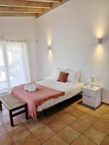 a bedroom with a large white bed and a bench at Paraiso da Serva - Flor do Rosto 2 in Odemira +23 photos